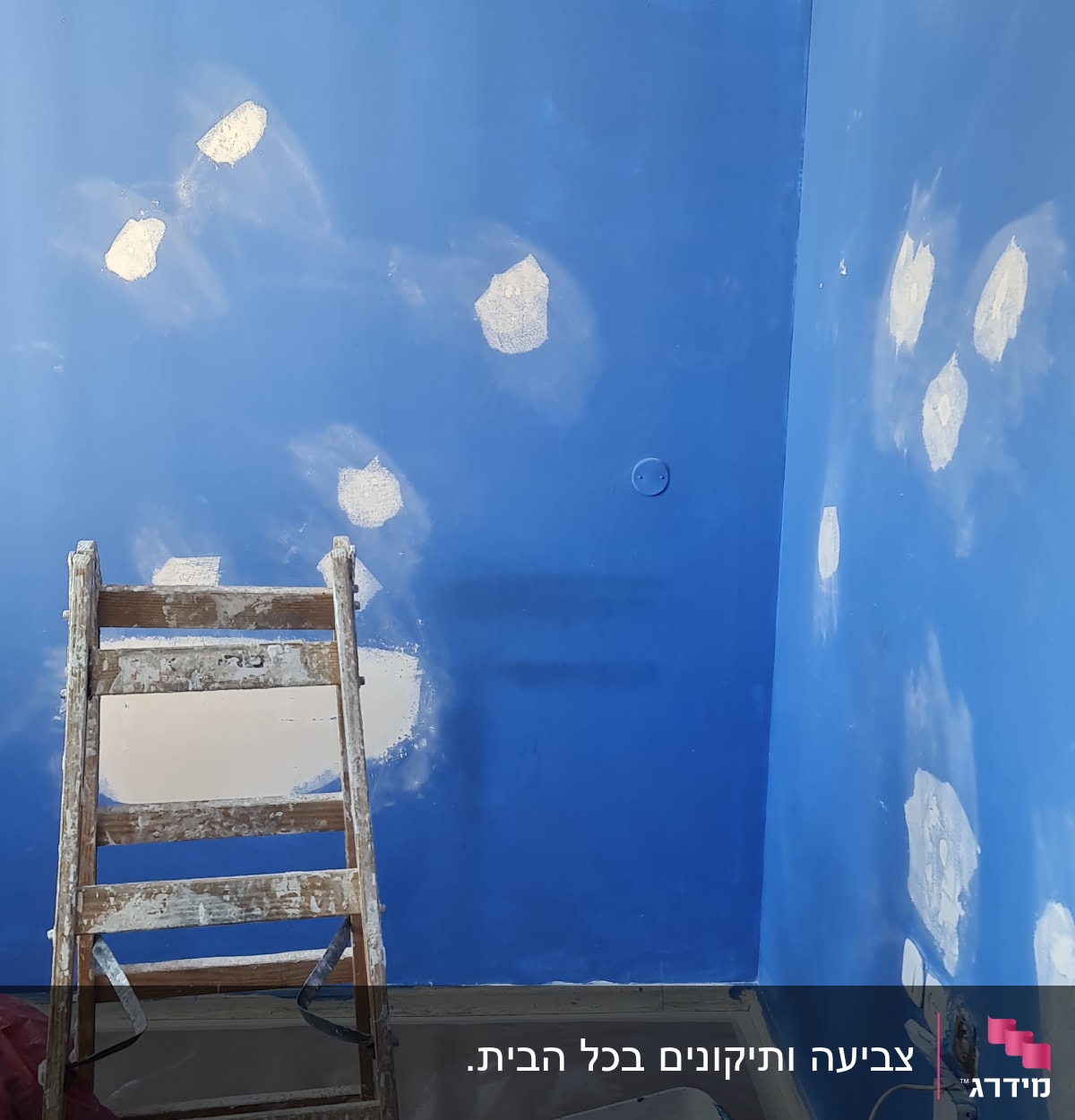 קיר כחול עם תיקוני צבע, סולם ודלי צבע